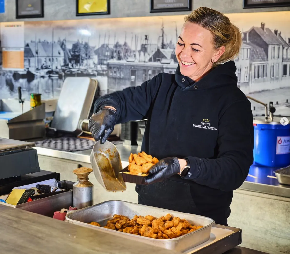 Medewerkster van Gerie's schept vers gebakken kibbeling in een bakje