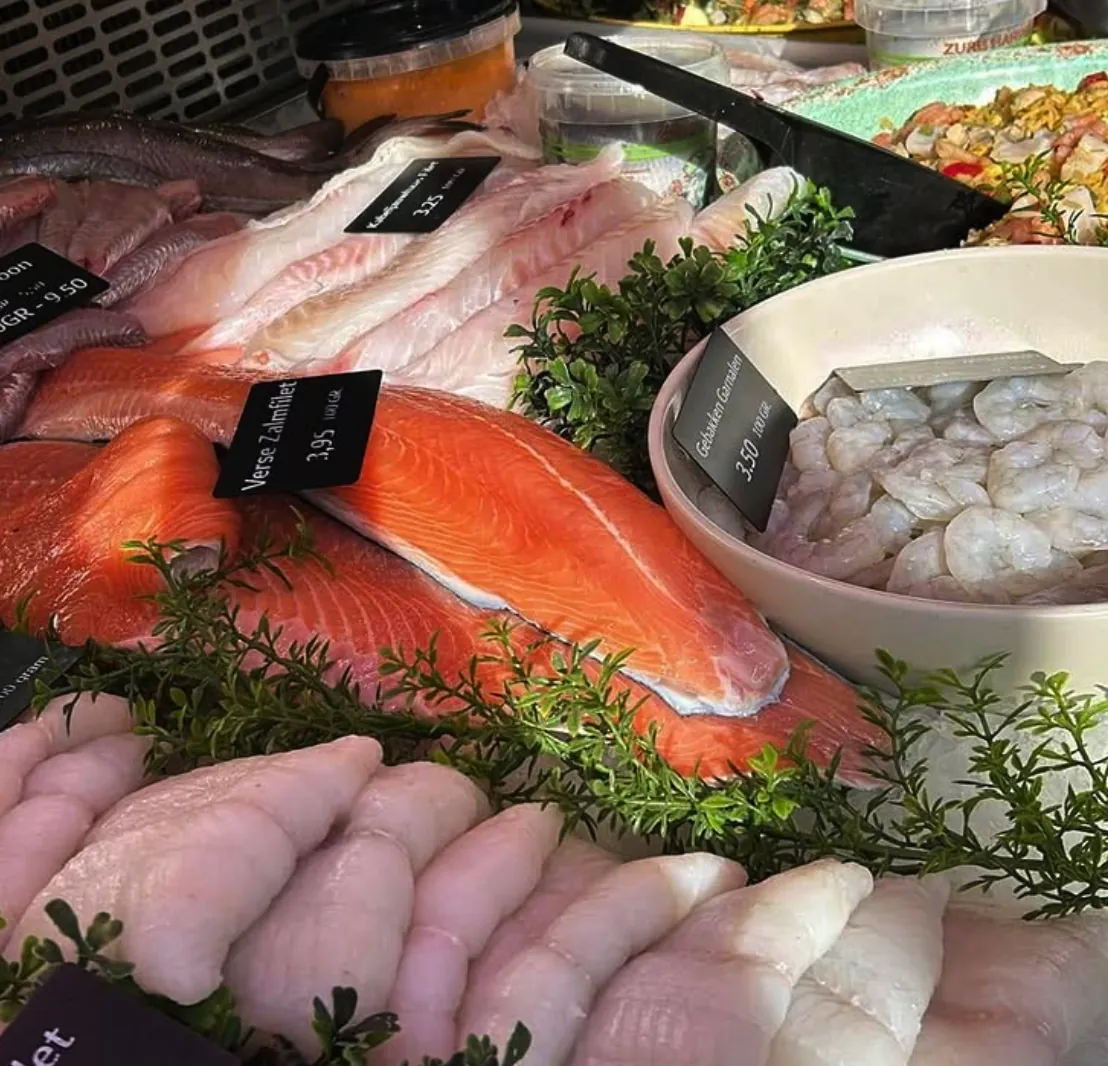 Verse visfilets met prijskaartjes in de koeltoonbank, waaronder zalmfilet en gepelde garnalen